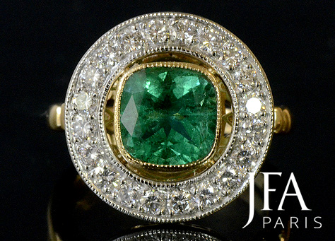 Très élégante bague de fiançailles en or jaune et platine. Elle est sertie en son centre d'une émeraude coussin et d'un entourage de diamants.
