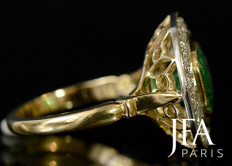 Très élégante bague de fiançailles en or jaune et platine. Elle est sertie en son centre d'une émeraude coussin et d'un entourage de diamants.